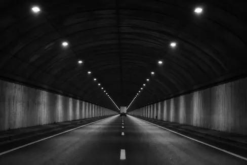 Caminhão de carga em túnel rodoviário iluminado à noite.